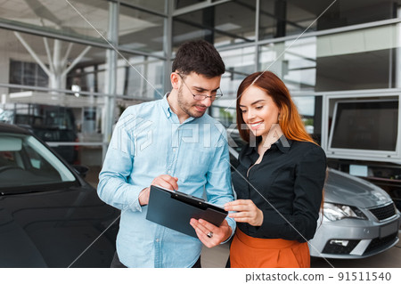 Car showroom seller gives papers to a client. 91511540
