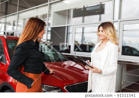 Car dealership manager shows documents for a deal to a client. 91511541