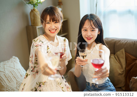 Two women chatting with a glass in their hands 91513312