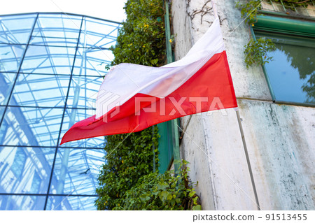 Flag of Poland on facade of a building waving in the wind. Symbol of national patriotism. Summer time 91513455