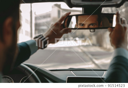 Adorable businessman is adjusting image reflection in the car Adorable businessman is adjusting image reflection in the car 91514523
