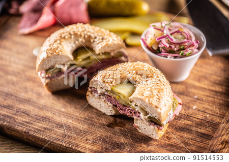 Bagel filled with juicy beef pastrami together with pickles 91514553