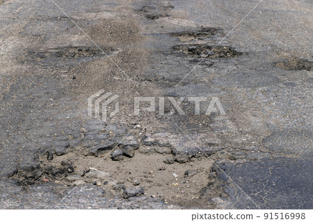 poor paved road with a lot of holes and potholes poor paved road with a lot of holes and potholes 91516998
