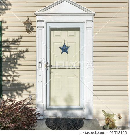 Square frame Exterior of a front door with blue star, doorbell, vinyl siding walls and windows Square frame Exterior of a front door with blue star, doorbell, vinyl siding walls and windows 91518123