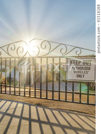 Vertical Iron gate against houses and ocean view with bright sun in the scenic blue sky 91518168
