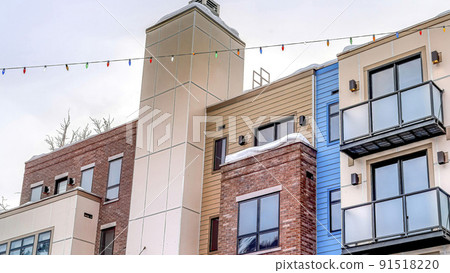 Pano Facade of modern townhouses with snowy flat roof and stairs at front entrances 91518220
