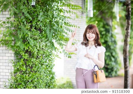 Green background: young woman pointing 91518300