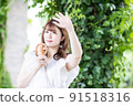 A young woman holding a handy fan and holding her hand dazzlingly 91518316