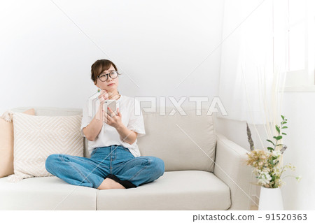 在家沙發上使用智能手機的女性（問題/擔憂） 91520363