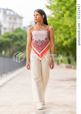 Trans woman walking distracted along a urban park 91522417