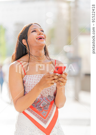 Trans woman laughing and using the mobile outdoors 91522418