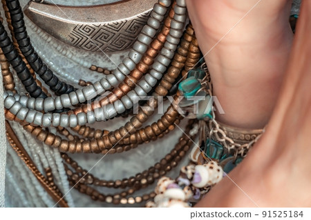 Close up of beautiful tribal boho style woman hands with lots of accessories. Boho style for fashionable look on resort. Middle aged well looking woman in white dress and boho style braclets. 91525184