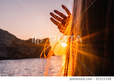 A young tourist Woman holding coffee tumbler cup while sitting outdoor and enjoying sunrise over sea mountain landscape. Women's yoga fitness routine. Healthy lifestyle, harmony and meditation 91525186