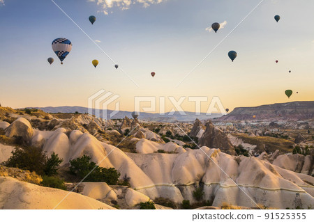 Hot air balloons flying over a volcanic landscape at Cappadocia, Turkey 91525355