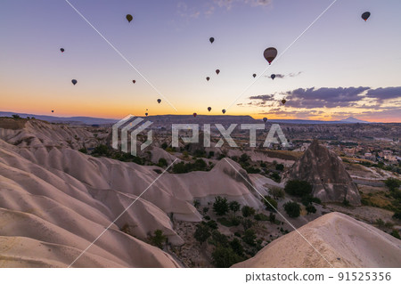Hot air balloons flying over a volcanic landscape at Cappadocia, Turkey 91525356