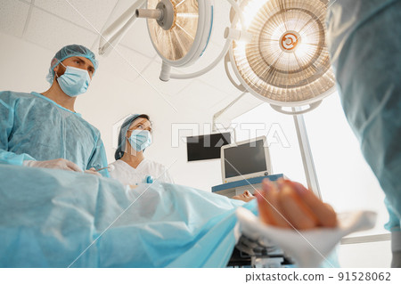 Focused surgical team working with a patient in an operation room Focused surgical team working with a patient in an operation room 91528062