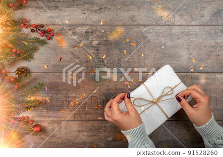 Womans hands open gift or present box decorated confetti on wooden background with holiday lights. top view. Flat lay composition for Christmas holidays. copy space 91528260