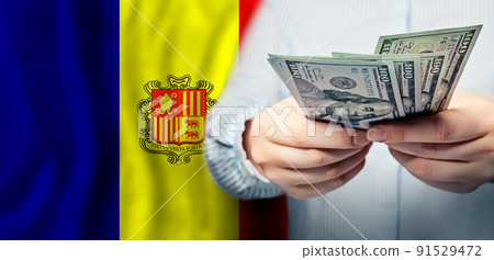 Hands holding US 100 dollars banknotes against flag of Andorra background 91529472