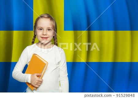 Kid girl with book standing against Swedish flag background. School and education in Sweden concept 91529848