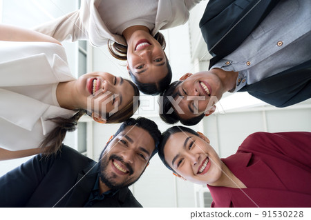 Portrait closeup bottom view happy faces of employees team standing in circle, looking at camera. 91530228