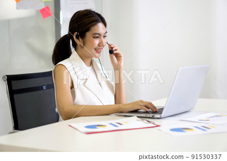 Young asian businesswoman adjusting the headset with mic prepare for online meeting through laptop computer. Working concept social distancing, quarantine, and isolation 91530337