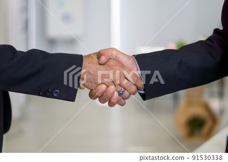 Business partners shaking hands in the modern office. Closeup 91530338