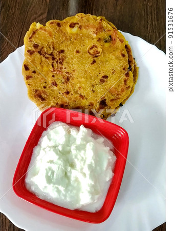 Indian breakfast dish.Stuffed potato paratha or channa dal paratha served with curd. Selective focus 91531676