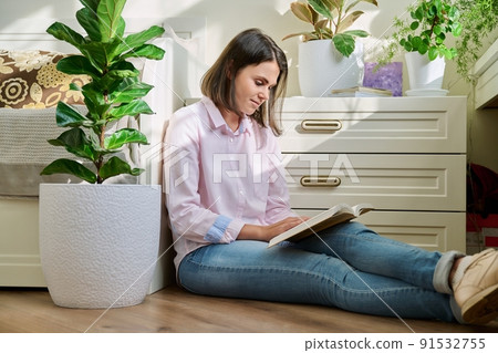 Young woman reading book sitting on the floor at home Young woman reading book sitting on the floor at home 91532755
