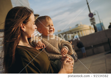 beautiful caucasian young mom holding baby son at the quay of city Saint-Petersburg, Russia beautiful caucasian young mom holding baby son at the quay of city Saint-Petersburg, Russia 91534382