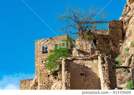 ruins of stone houses attached to the rock in the depopulated village of Gamsutl in Dagestan 91535609