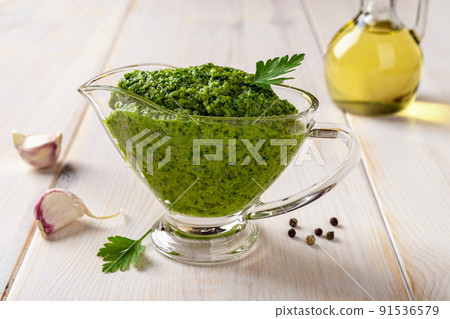 Green sauce in a gravy boat on a table. Chimichurri dipping sauce from fresh parsley. Green sauce in a gravy boat on a table. Chimichurri dipping sauce from fresh parsley. 91536579