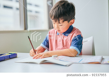 Elementary school boy writing in a notebook Elementary school boy writing in a notebook 91537955