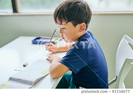 Elementary school boy writing in a notebook 91538077