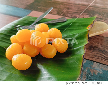 Thong Yod or Round Egg Yolk Tart, an ancient Thai dessert, orange and gold, has a sweet taste on banana leaf Thong Yod or Round Egg Yolk Tart, an ancient Thai dessert, orange and gold, has a sweet taste on banana leaf 91538409