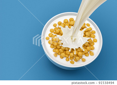 Corn balls with pouring milk on blue background, top view 91538494