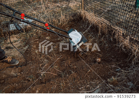 Male farmer plows the land with a cultivator. Agricultural machinery for tillage in the garden, combine harvester. 91539273