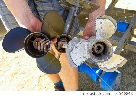 man changing propeller on outboard motor. Repairing outboard motor for boat, replacing screw. 91540848
