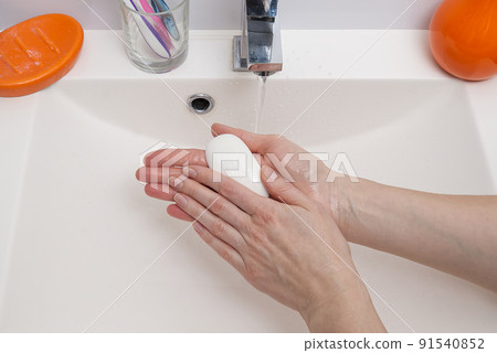 woman washing hands with white soap over white sink in bathroom, closeup. primitive covid virus protection. 91540852