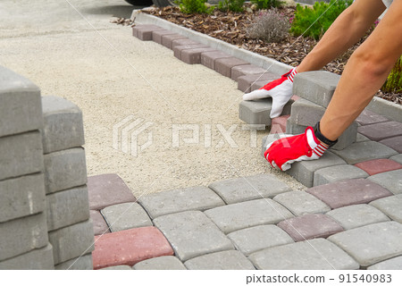 worker laying paving stones. stone pavement, construction worker laying cobblestone rocks on sand. 91540983