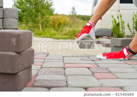 worker laying paving stones. stone pavement, construction worker laying cobblestone rocks on sand. 91540989