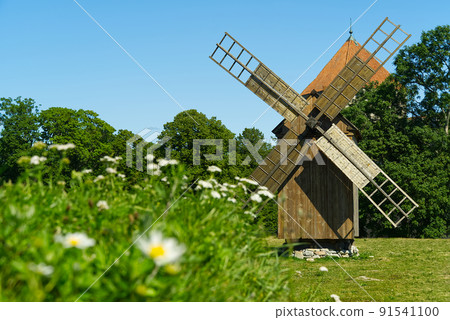 Old vintage wooden windmill in the background of the summer field. Saaremaa, Estonia. 91541100
