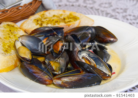 Mussels with white bread on a white plate. 91541403