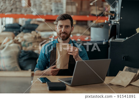 Business owner holding roasted coffee beans in paper bag in coffee factory Business owner holding roasted coffee beans in paper bag in coffee factory 91541891