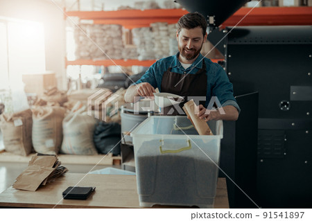 Business owner packs roasted coffee beans into packages for sale 91541897