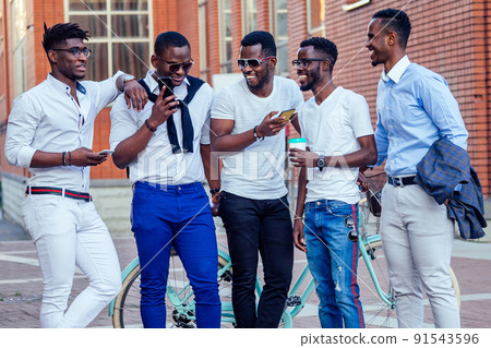 fashionable friends at a meeting. a group of five handsome African American men well-dressed businessmen having fun and communicating in the summer in the park fashionable friends at a meeting. a group of five handsome African American men well-dressed businessmen having fun and communicating in the summer in the park 91543596