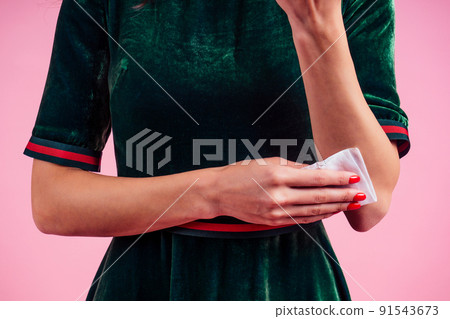 part of the body of a young woman in a pink studio . girl using wet wipes the sweat hand applying hand sanitizer on a pink background in the studio 91543673