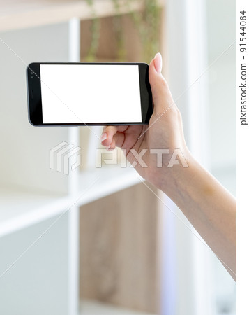 Online connection. Mobile mockup. Digital technology. Male hand holding smartphone with blank screen in light room interior. Online connection. Mobile mockup. Digital technology. Male hand holding smartphone with blank screen in light room interior. 91544084