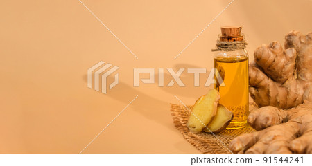 Glass bottle of essential ginger oil, ginger root on beige background. Healthy food eating concept. Zingiber officinale Essential oil. Natural cosmetics ingredients for skincare, body and hair care 91544241