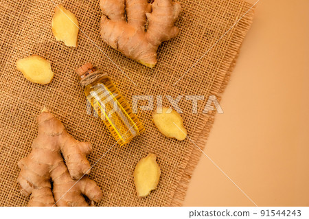Glass bottle of essential ginger oil, ginger root on beige background. Healthy food eating concept. Zingiber officinale Essential oil. Natural cosmetics ingredients for skincare, body and hair care Glass bottle of essential ginger oil, ginger root on beige background. Healthy food eating concept. Zingiber officinale Essential oil. Natural cosmetics ingredients for skincare, body and hair care 91544243