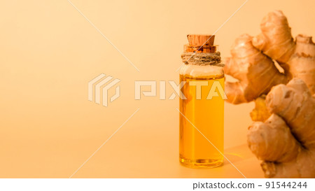 Glass bottle of essential ginger oil, ginger root on beige background. Healthy food eating concept. Zingiber officinale Essential oil. Natural cosmetics ingredients for skincare, body and hair care 91544244